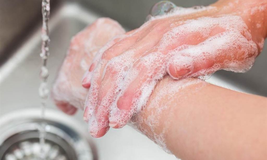 A close up of a person washing their hands in a sink.