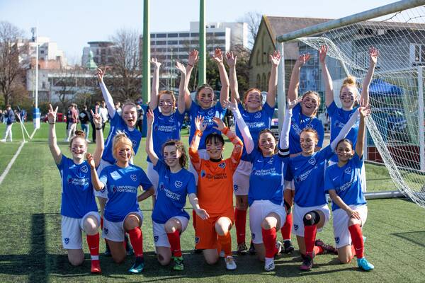 Eleven women in football kits celebrating